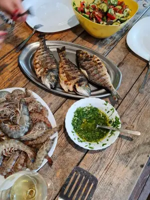 a table topped with plates of seafood and a salad at Holiday Home Kite House in Ulcinj