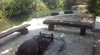 a picnic table and bench next to a river at Holiday Home Kite House in Ulcinj