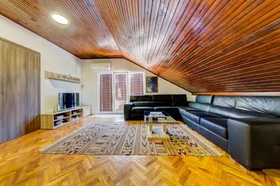 a living room with a leather couch and a wooden ceiling at Castelomi in Podgorica