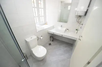a white bathroom with a toilet and a sink at Katareo Apartments in Kotor