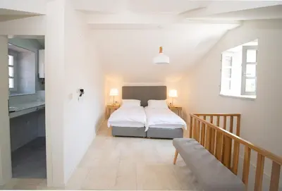 a white bedroom with a bed and a staircase at Katareo Apartments in Kotor