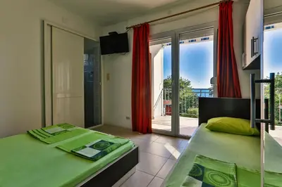 a bedroom with two beds and a balcony with sliding glass doors at Apartments Venezia in Sutomore