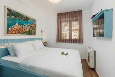 a bedroom with a white bed and a window at Apartments Los Olivos in Kotor