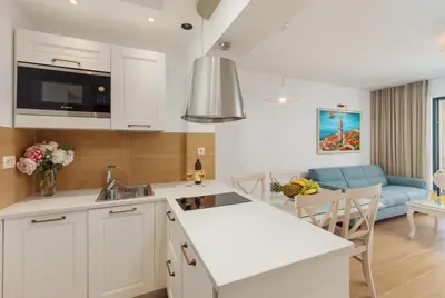 a kitchen with white cabinets and a blue couch at Apartments Los Olivos in Kotor