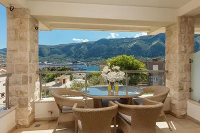 a balcony with a table and chairs and mountains at Apartments Los Olivos in Kotor