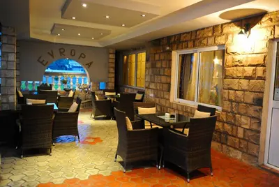 a restaurant with chairs and tables and a stone wall at Hotel Evropa in Podgorica