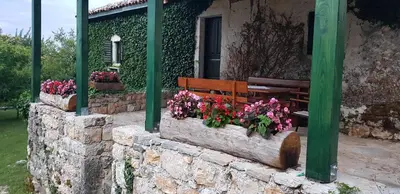 a bench and flowers in front of a building at Old house Nilovic in Livari
