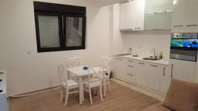a white kitchen with a table and chairs in it at Apartment More in Budva