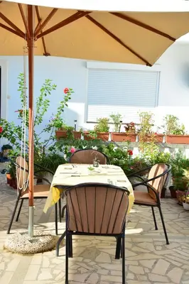 a table and chairs under an umbrella on a patio at Guest House Vera in Ulcinj