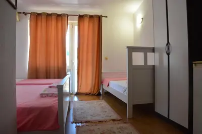 a bedroom with two beds and an orange curtain at Guest House Vera in Ulcinj