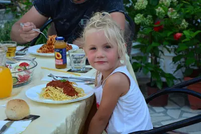 a little girl sitting at a table with a plate of spaghetti at Guest House Vera in Ulcinj
