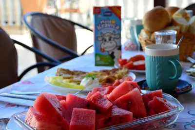 a table with a plate of watermelon and a plate of food at Guest House Vera in Ulcinj