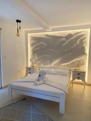 a white bedroom with a bed and two night stands at Apartments Dzaleta in Sveti Stefan