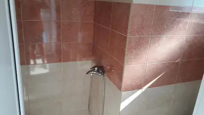 a shower with a glass door with a shower facet at Apartmani 