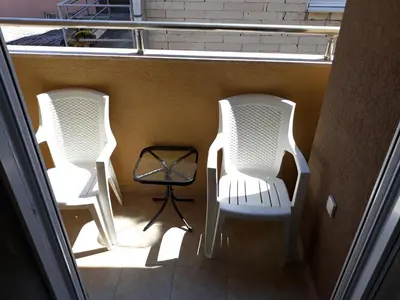 two white chairs and a table on a balcony at Apartmani 