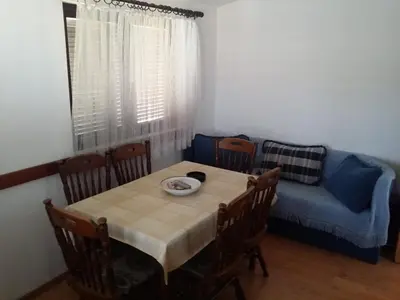 a dining room with a table and a blue couch at Apartman Tripkovic in Bar