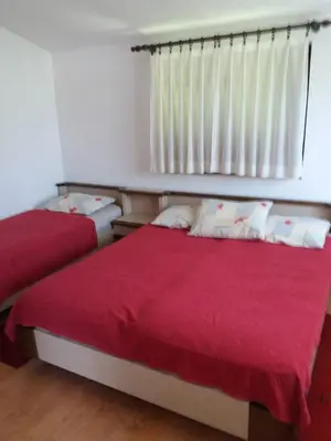 a bedroom with two beds with red sheets and a window at Apartman Tripkovic in Bar