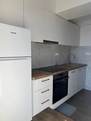 a white kitchen with a refrigerator and a sink at Azzure Apartment in Ulcinj