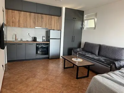 a kitchen and a living room with a couch and a table at Azzure Apartment in Ulcinj