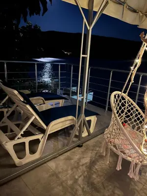 a couple of chairs and an umbrella on a balcony at night at Azzure Apartment in Ulcinj