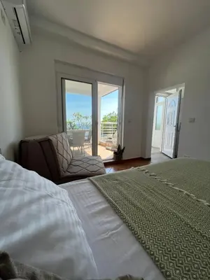 a bedroom with a bed and a chair and a balcony at Azzure Apartment in Ulcinj
