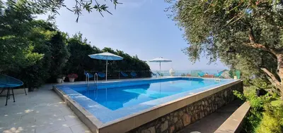 a swimming pool with chairs and umbrellas on a wall at Boutique Home Saltaragazza in Petrovac na Moru