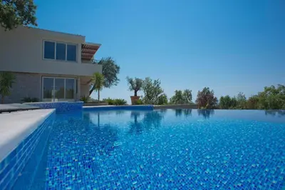a large blue swimming pool in front of a house at Luxury Villa Crystal Blue in Sveti Stefan