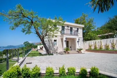 a large white house with a tree in front of it at Luxury Villa Crystal Blue in Sveti Stefan