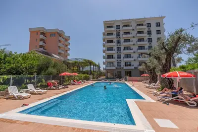 a swimming pool with chairs and umbrellas next to a building at Hotel Pharos in Bar