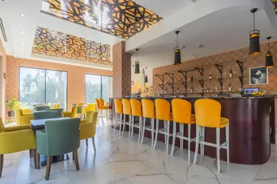 a restaurant with yellow chairs and a bar at Hotel Pharos in Bar