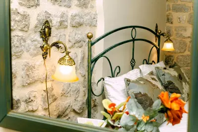 a bedroom with a bed with a lamp and a mirror at D & Sons Apartments in Kotor