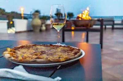 a pizza on a table with a glass of wine at Adriatic Apartment in Ulcinj