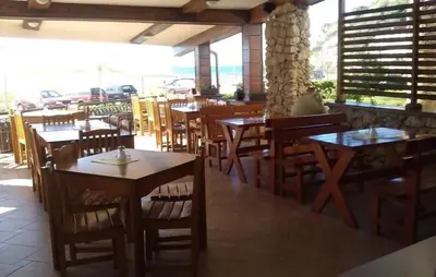 a restaurant with wooden tables and chairs and a person sitting at a table at Adriatic Apartment in Ulcinj