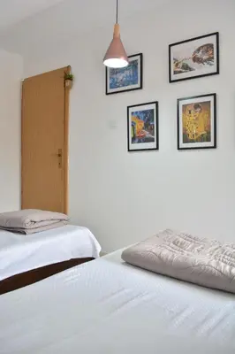 a bedroom with two beds and pictures on the wall at Apartman L&M in Cetinje