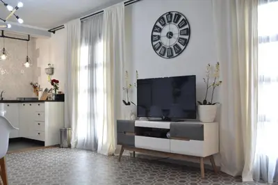 a living room with a tv and a clock on the wall at Apartman L&M in Cetinje