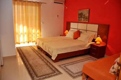 a bedroom with a large bed with red walls at Aparthotel Villa Primafila in Ulcinj