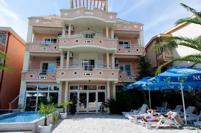 a large building with chairs and umbrellas next to a pool at Aparthotel Villa Primafila in Ulcinj