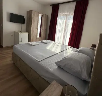 a bedroom with a large bed and a television at Rooms Ajllin in Ulcinj