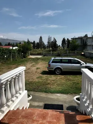 a white car parked in a yard next to a fence at Rooms Ajllin in Ulcinj