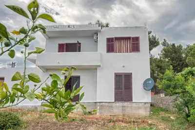 a white house with red shuttered windows at BOR - The Entire Home with Sea view in Ulcinj