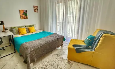 a bedroom with a bed and a yellow chair at Studio Lucica in Petrovac na Moru