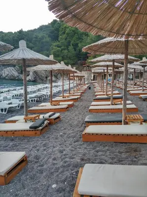a row of lounge chairs and umbrellas on a beach at Studio Lucica in Petrovac na Moru