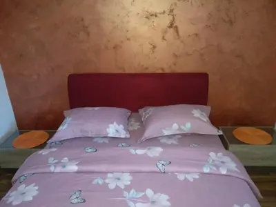 a bed with pink sheets and white flowers on it at Apartments Popovic in Podgorica
