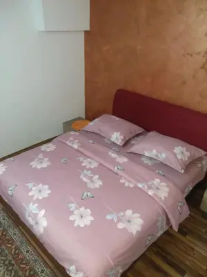 a pink bed with pink and white flowers on it at Apartments Popovic in Podgorica