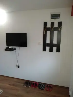 a wall with a flat screen tv and shoes on the floor at Apartments Popovic in Podgorica