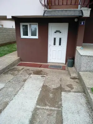 a small house with a white door and stairs at Apartments Popovic in Podgorica
