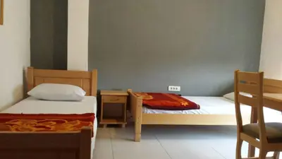 a bedroom with two beds and a table and a chair at Guest house Vila Vedesa in Kotor