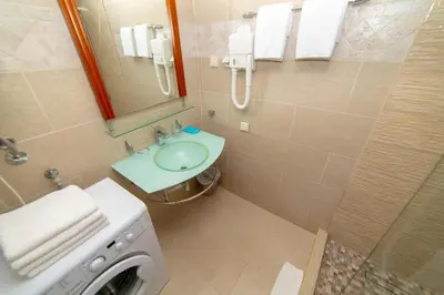 a bathroom with a sink and a shower and a washing machine at Ponta in Rafailovici