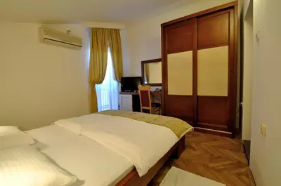 a bedroom with a bed and a wooden door at Vila Đurić - Ex Hotel Đurić in Petrovac na Moru