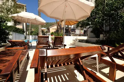 a group of benches and umbrellas on a patio at Vila Đurić - Ex Hotel Đurić in Petrovac na Moru